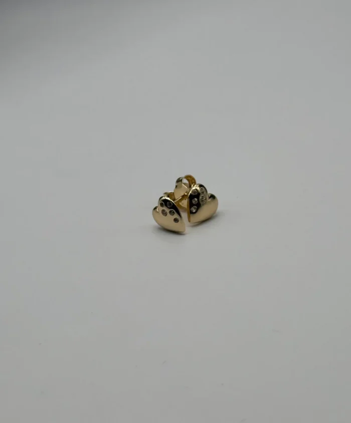 Aretes Corazón y circonia de Oro 14KT Par de aretes de oro 14KT con diseño de corazón y circonias engastadas, sobre superficie blanca. Joyería fina Venecia Gold.