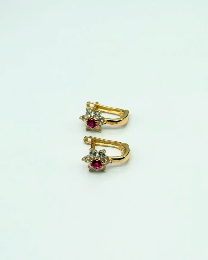 Par de argollas de oro 14KT Ley 585 para niñas, con diseño floral de circonias transparentes y rubí central, sobre fondo blanco. Joyería infantil Venecia Gold.